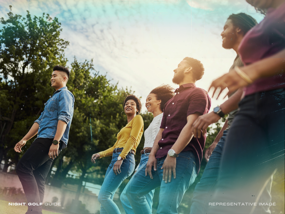 Friends walking to a bar after playing night golf, enjoying post-round nightlife
