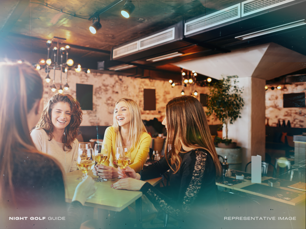 Women chatting and drinking at a bar after night golf