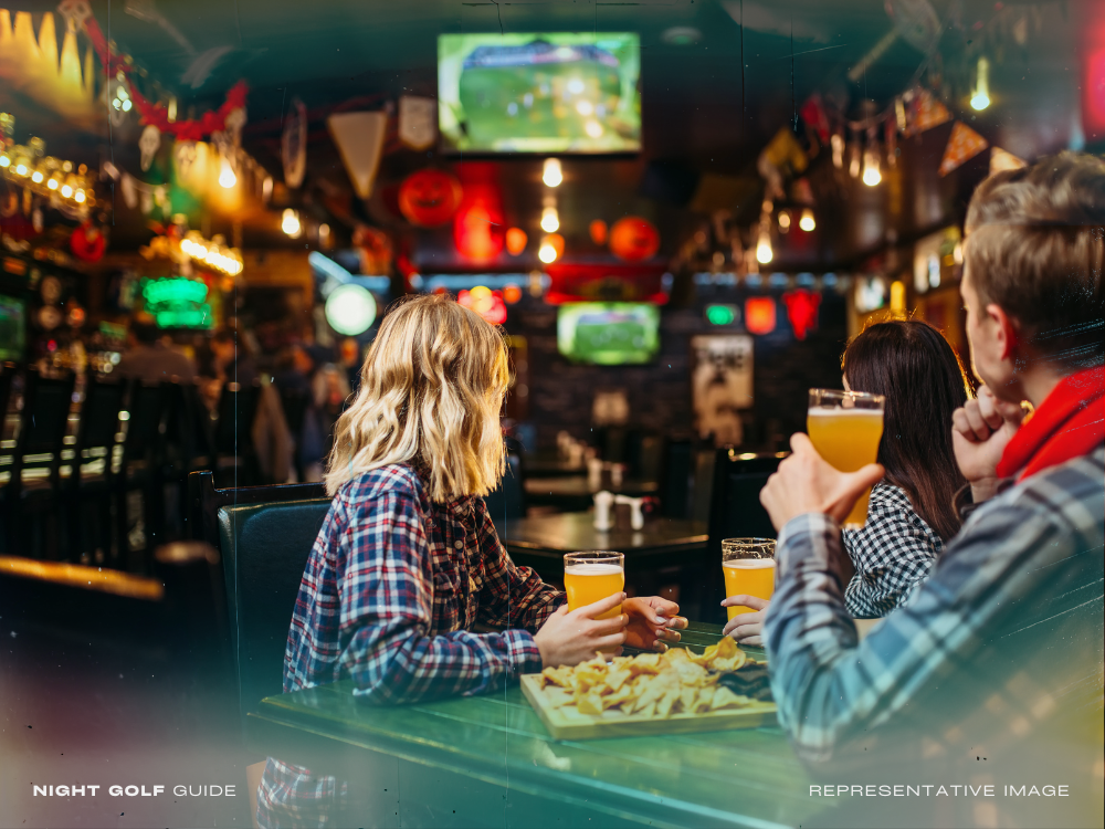 Patrons watching a sports game at a bar with food and drinks