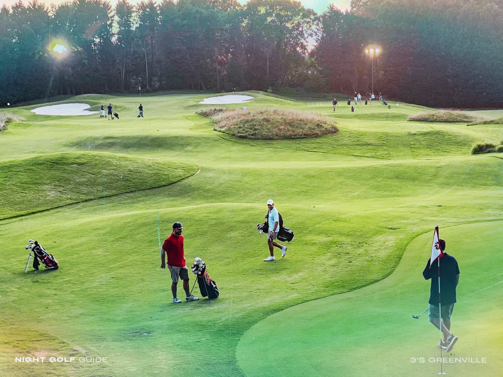 Group of golfers playing under lights at 3's Greenville at night