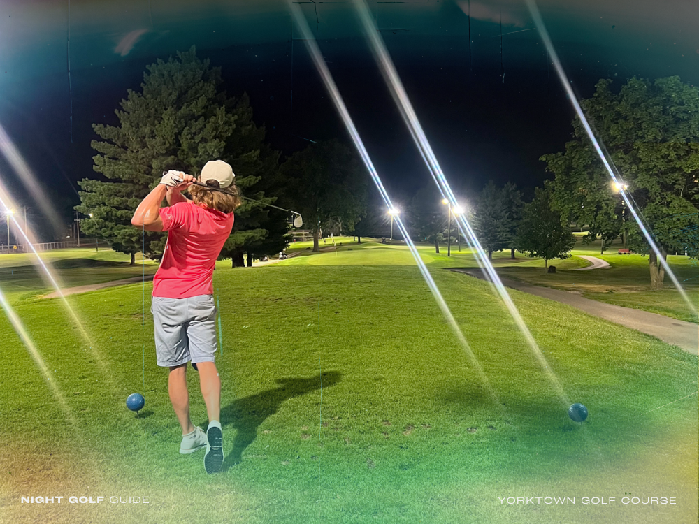Golfers playing under floodlights at Yorktown's night golf course with scenic clubhouse nearby